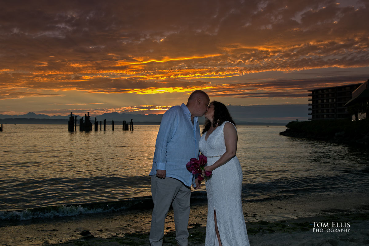 Ilene and Burt kiss on the beach at sunset during their Seattle wedding at Ray's Boathouse